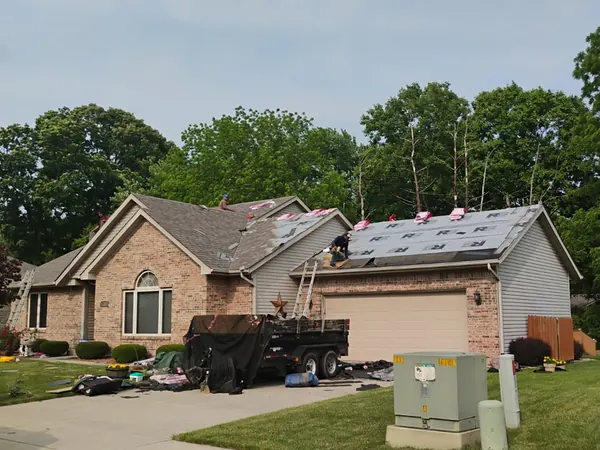 New shingle bundles on the roof of a brick home with a trailer in the driveway