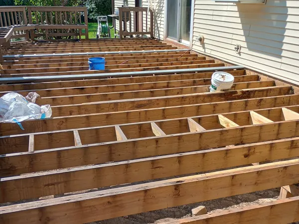New deck framing with joists laid out beside a house