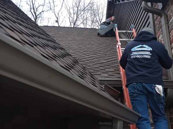 Worker on a ladder at the gutter line of a brick home