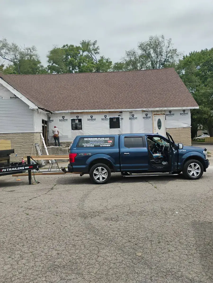 House with a large addition wrapped in house wrap and a pickup truck parked out front