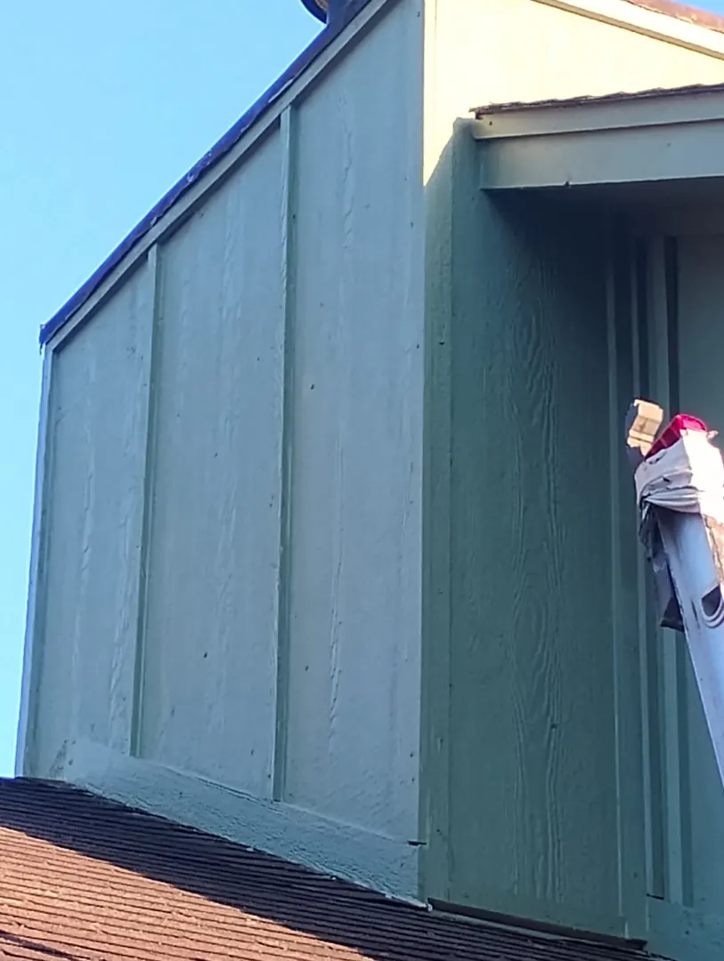 Blue-green painted LP SmartSide panel siding on an upper wall above a roof line