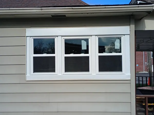 Tan-sided house with new white windows