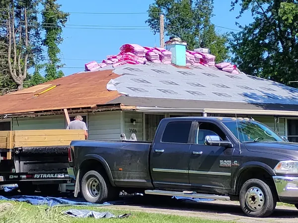 Ranch house mid-reroof with new underlayment down and a pickup in the driveway