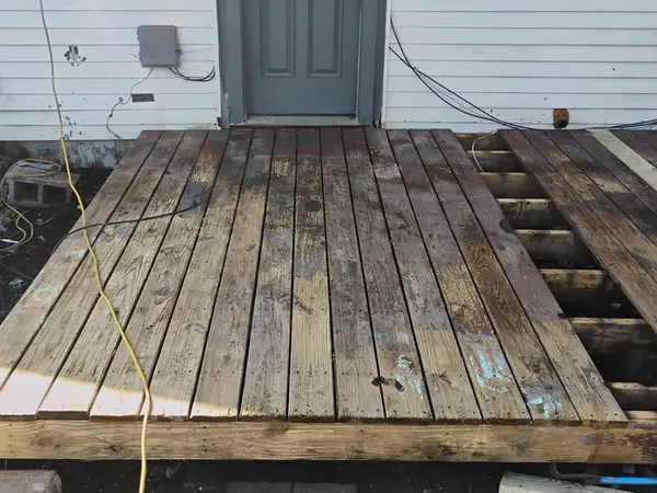 Old deck with rotted, sagging boards at a back door