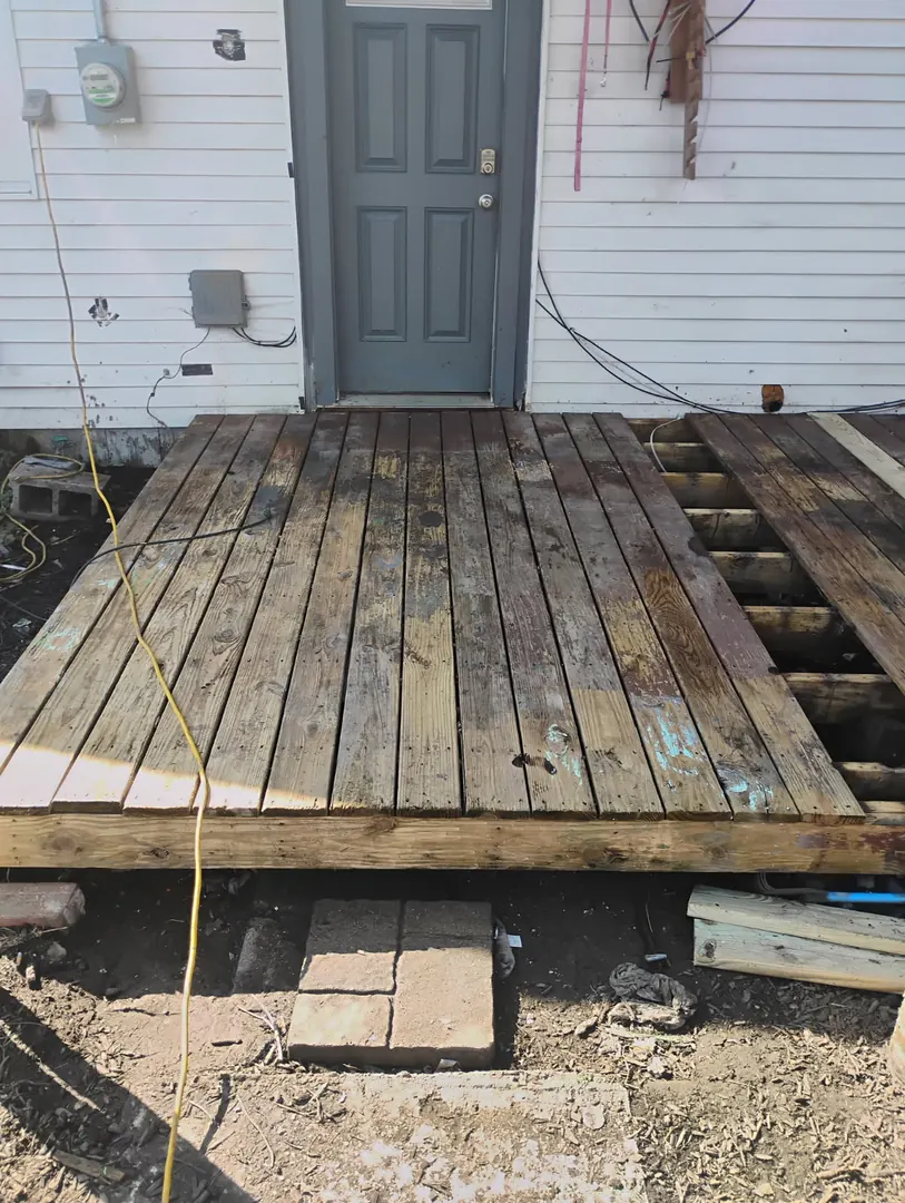 Weathered, gray wooden deck boards and steps pulling apart outside a back door