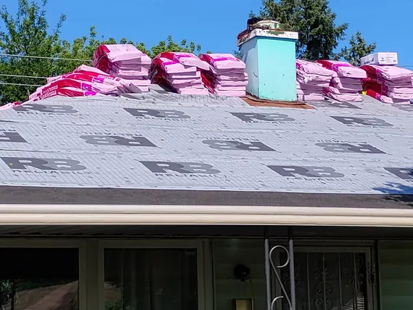 New shingle bundles staged along the ridge of a roof