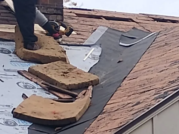 Close-up of old shingles being pried off the roof deck