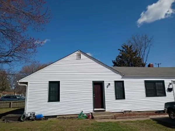 Ranch house finished in white vinyl siding with dark windows