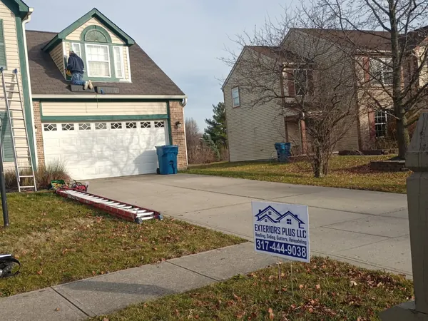 Finished two-story home with a contractor yard sign in the front lawn